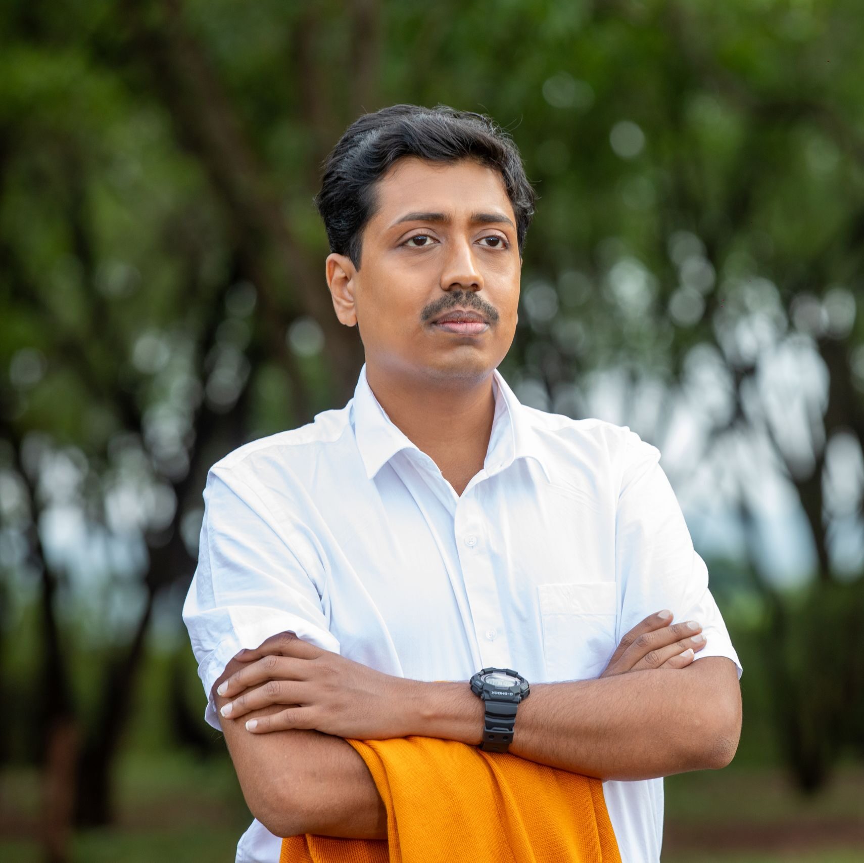 Portrait of a confident man outdoors in a casual pose with an orange shawl.